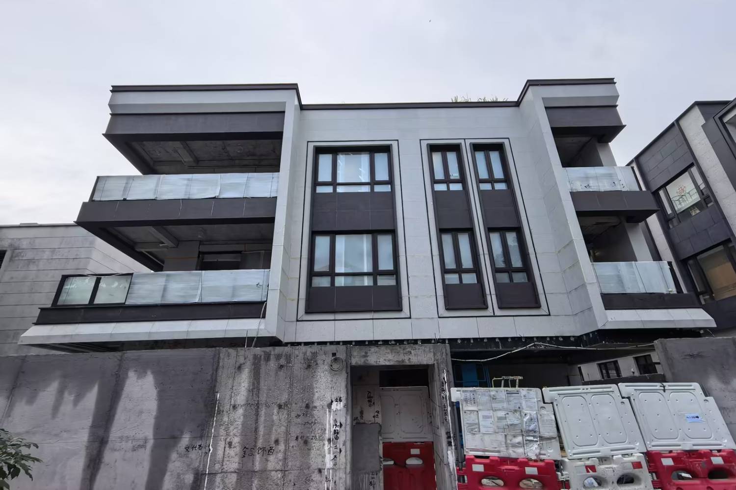成鵬工程香港紫藤路別墅項目施工現場圖，展示別墅外牆鋁板、鐵欄河扶手及入口不鏽鋼門。